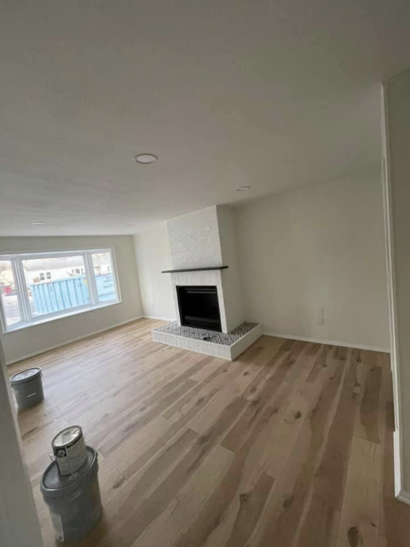 After — renovated living room with new hardwood floors and tiled fireplace